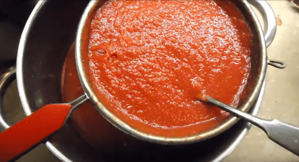 Процеживание томатного пюре через сито