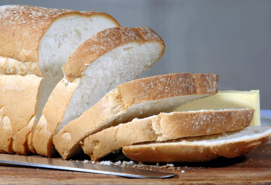 Нарезанная буханка белого хлеба и нож на столе