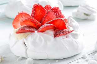 Meringue nest with strawberries dusted in icing sugar